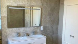 A bathroom with a double sink vanity, a large mirror, and a white wardrobe.
