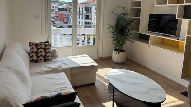 A modern living room with a sofa, a coffee table, and a TV on a shelf.