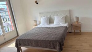 A bedroom with a bed, bedside tables, and a window.