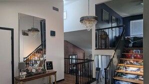 A staircase with a wooden finish and black railings, leading to a second floor.