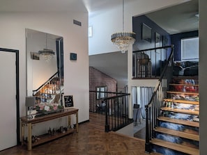 A staircase with a wooden finish and black railings, leading to a second floor.
