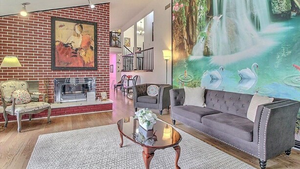 A living room with a fireplace, a large painting of a waterfall, and a sofa.
