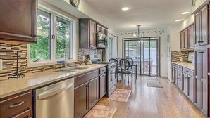 A modern kitchen with dark wood cabinets, stainless steel appliances, and a large window providing a view of the outdoors.