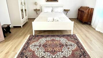 Ein Schlafzimmer mit einem großen Bett, einem Spiegelkorpus, einer Holzkommode und einem gemusterten Teppich.
