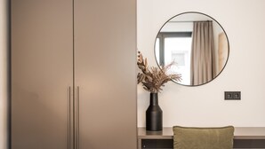 Ένα μοντέρνο δωμάτιο με μια ντουλάπα, έναν καθρέφτη, ένα βάζο με αποξηραμένα φυτά και μια καρέκλα.