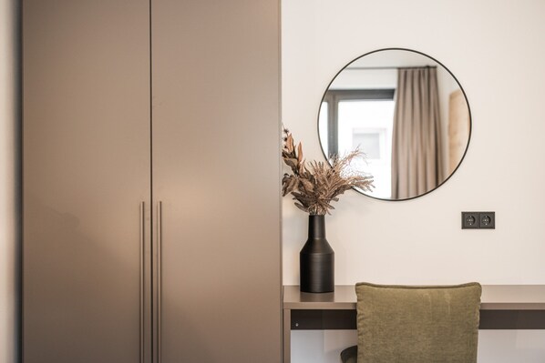 A modern room with a wardrobe, a mirror, a vase with dried plants, and a chair. - Apartment Near Schaterzlift Kirchberg (Kirchberg in Tirol)