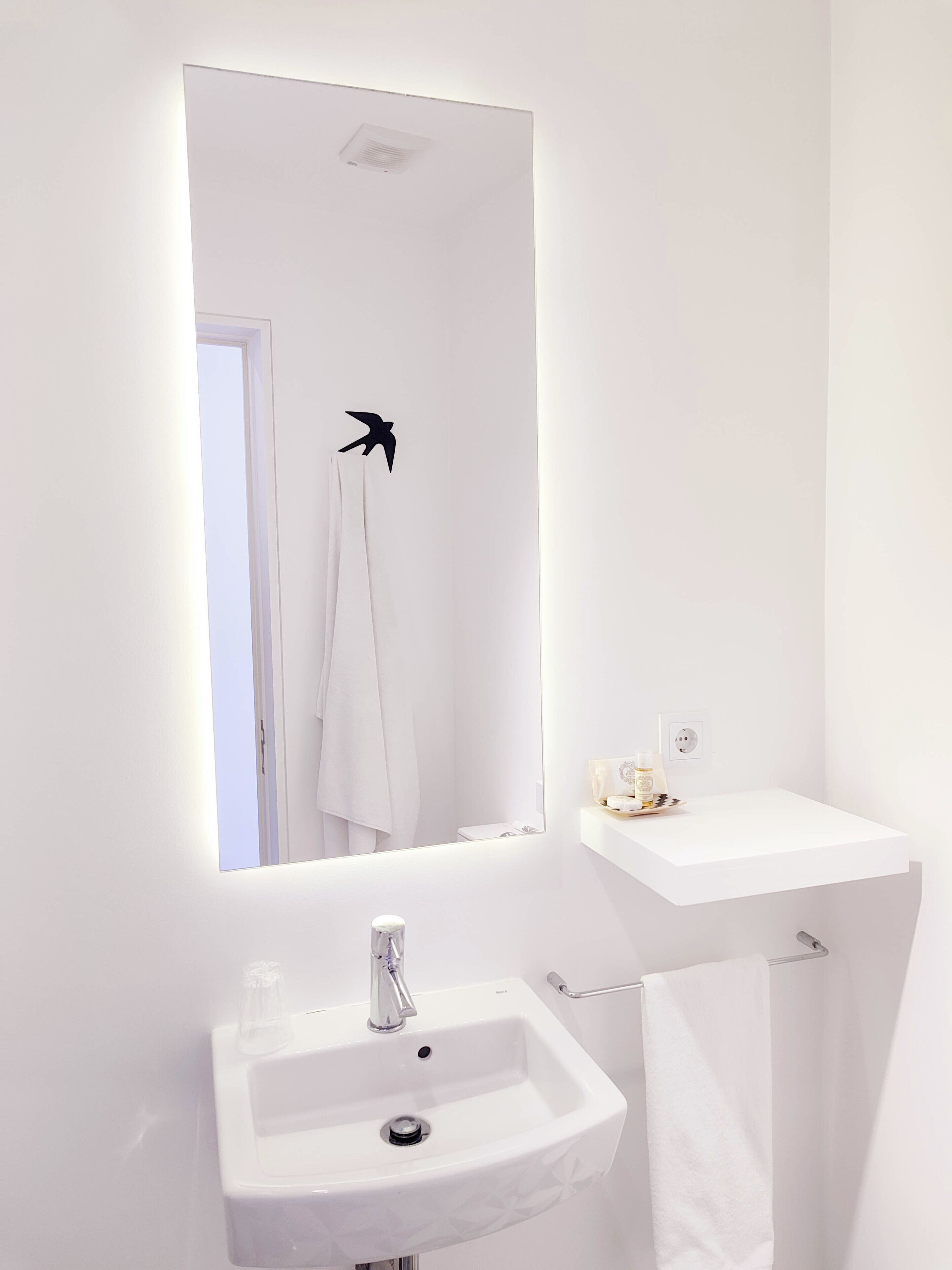 A bathroom with a white sink, a mirror, and a towel rack.