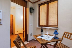 A small wooden table with a bottle and wine glass, a lantern, and a chair in a corner with a window. - Elegant apartment in the setting of Siena with air conditioning, WI-FI and TV (Siena)