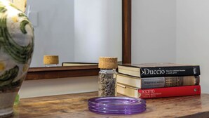 A wooden table with a vase, a small bottle with cork stopper, and a stack of books.