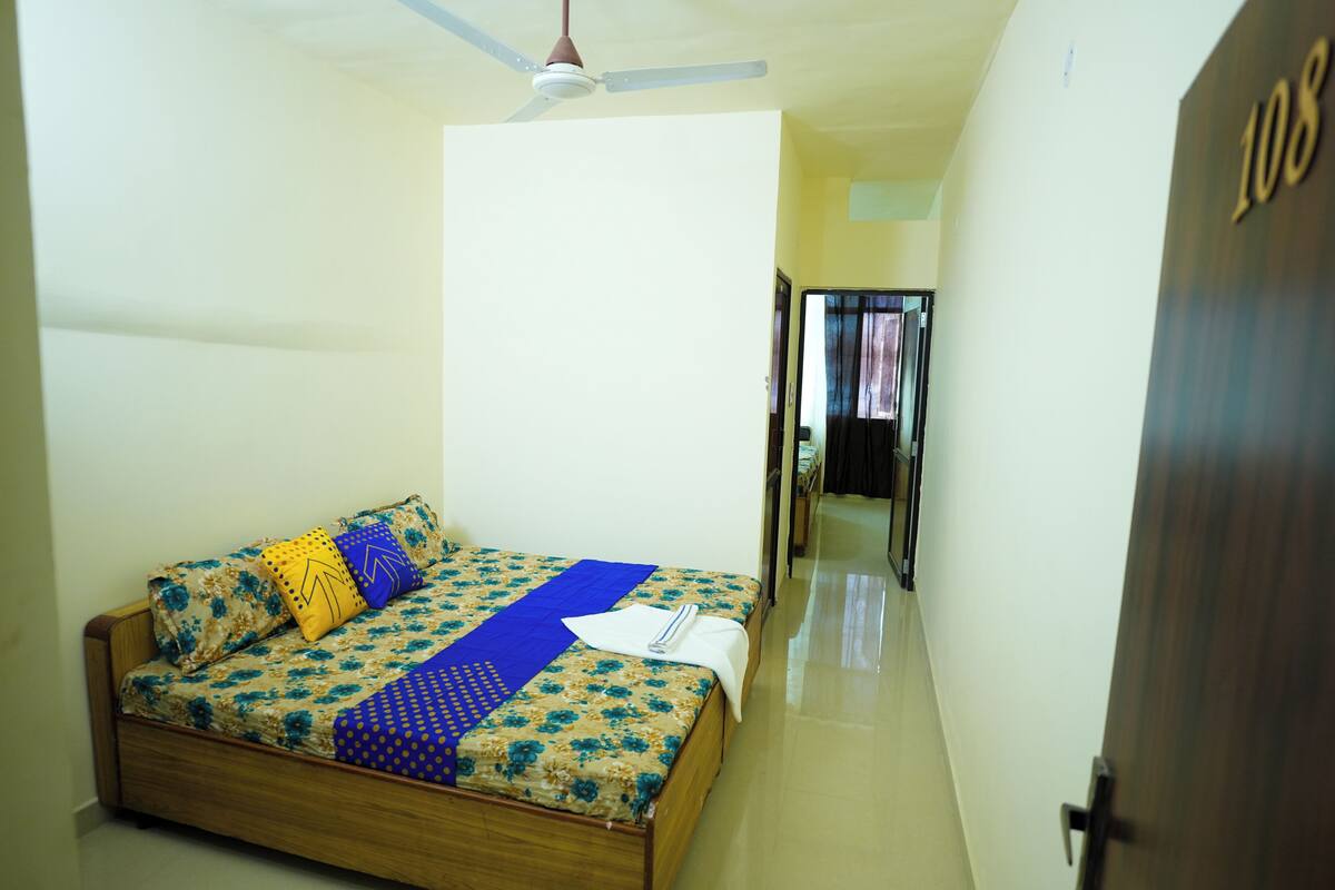 A hotel room with a bed, a ceiling fan, and a door marked with the number 108.