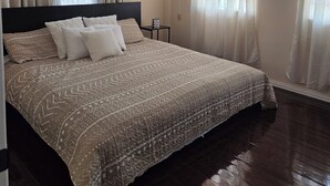 A bedroom with a large bed, wooden flooring, and a ceiling with exposed beams. - 3 min from Ogle Intl Airport 
Vacation Home in Prime Location (Ogle)