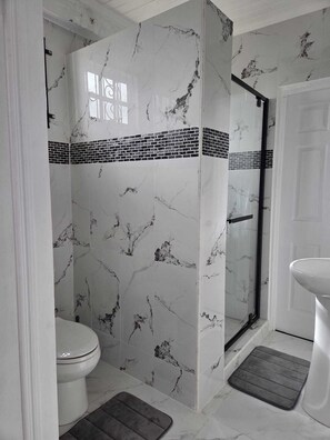 Een douche, handdoeken, zeep, toiletpapier