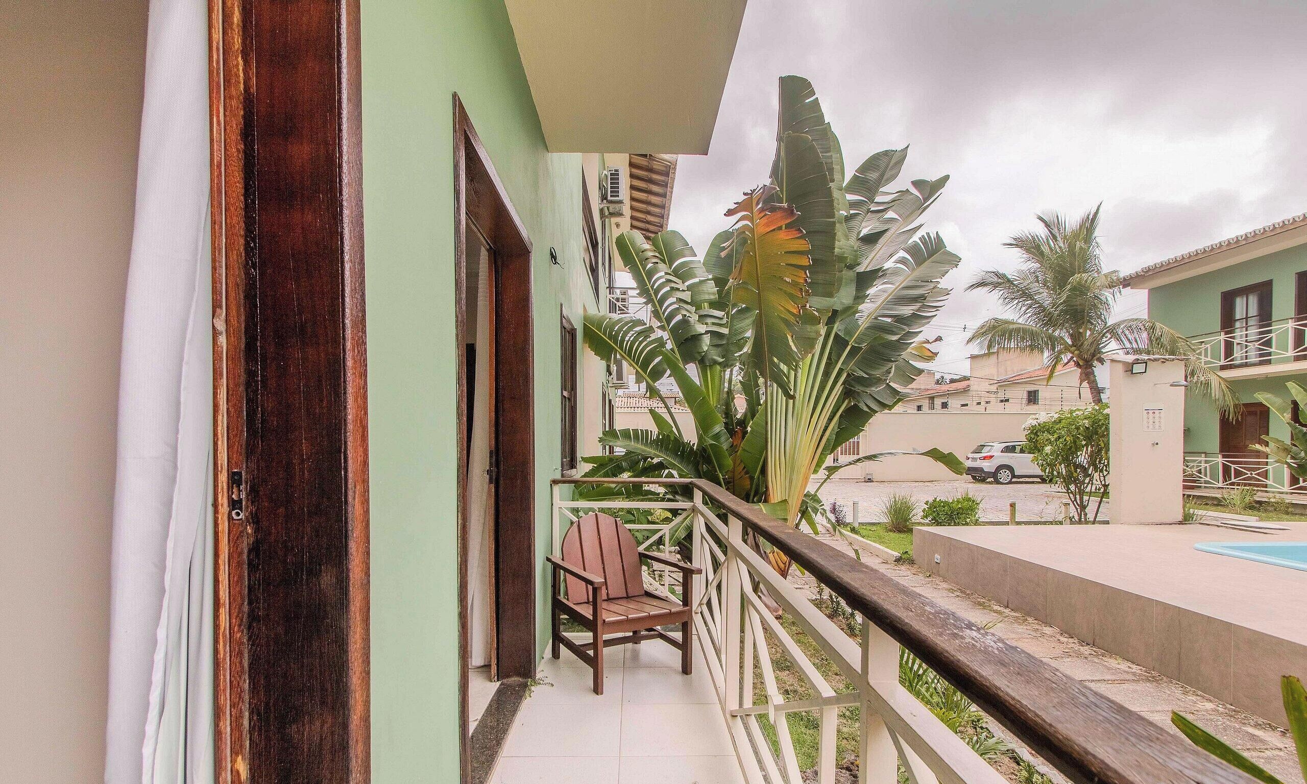 Varanda com cadeira, piscina e plantas tropicais.