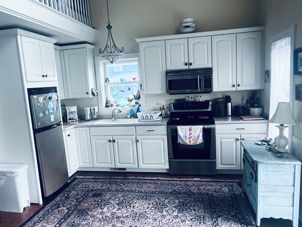 A kitchen with white cabinets, a stainless steel refrigerator, a microwave, and a stove.