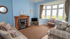 A living room with a fireplace, a television, and two sofas. - Glenavon (Seahouses)
