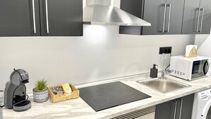 A modern kitchen with a built-in stove, a coffee maker, a microwave, and a sink. - Naffah Apartments II (Madrid)