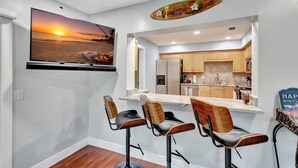 A modern kitchen with wooden cabinets, a built-in island, and bar stools.