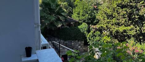 Un balcón con vista a un paisaje urbano y abundante vegetación.