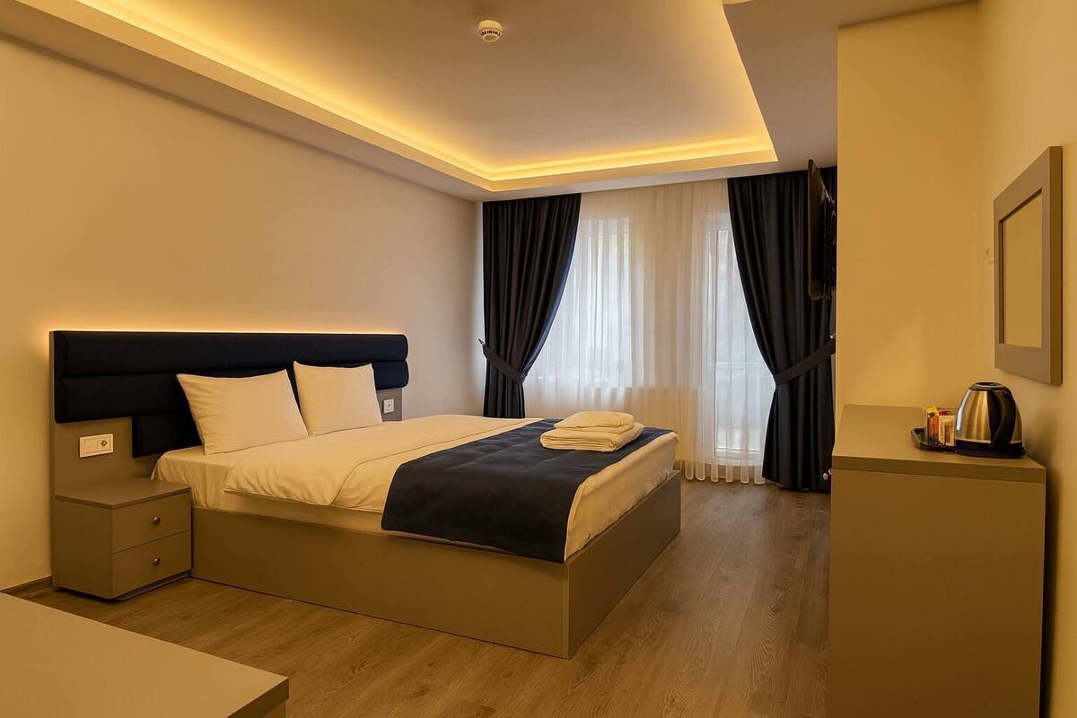 A modern hotel room with a large bed, bedside tables, a desk, and a coffee maker.