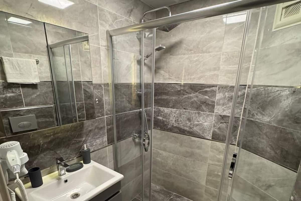 A modern bathroom with a glass-enclosed shower, a white sink, and a toilet.