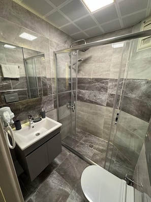 Een aparte badkuip en douche, een haardroger, handdoeken, zeep