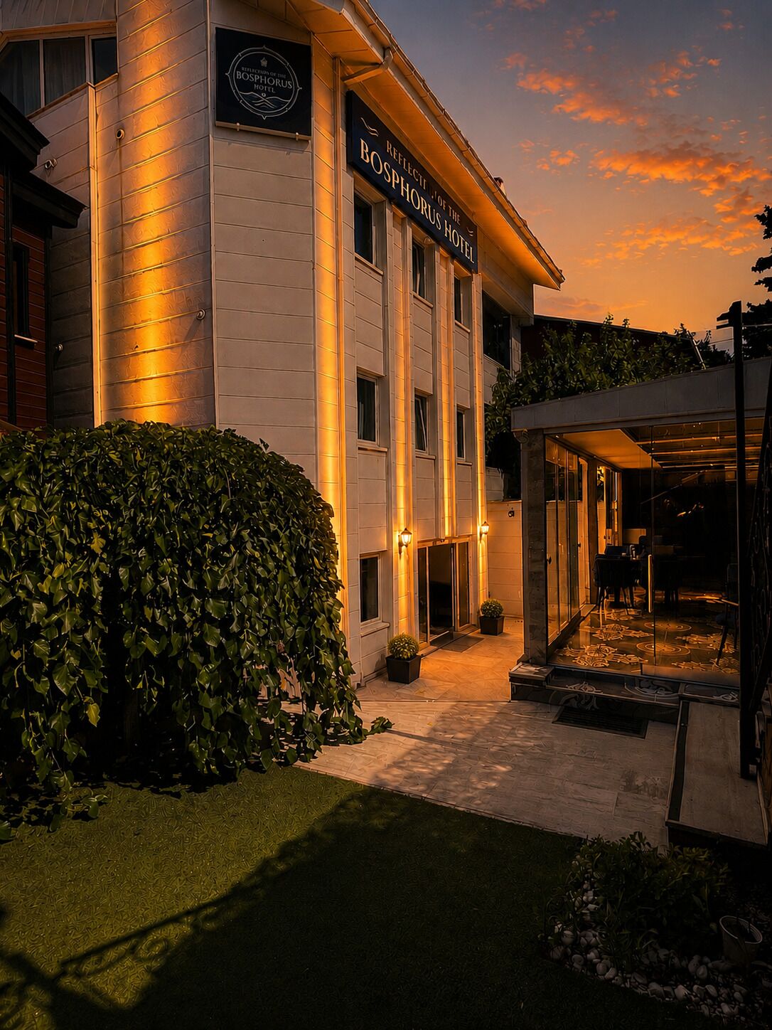 A hotel with a well-lit entrance, a covered outdoor area, and a sign indicating the hotel's name.