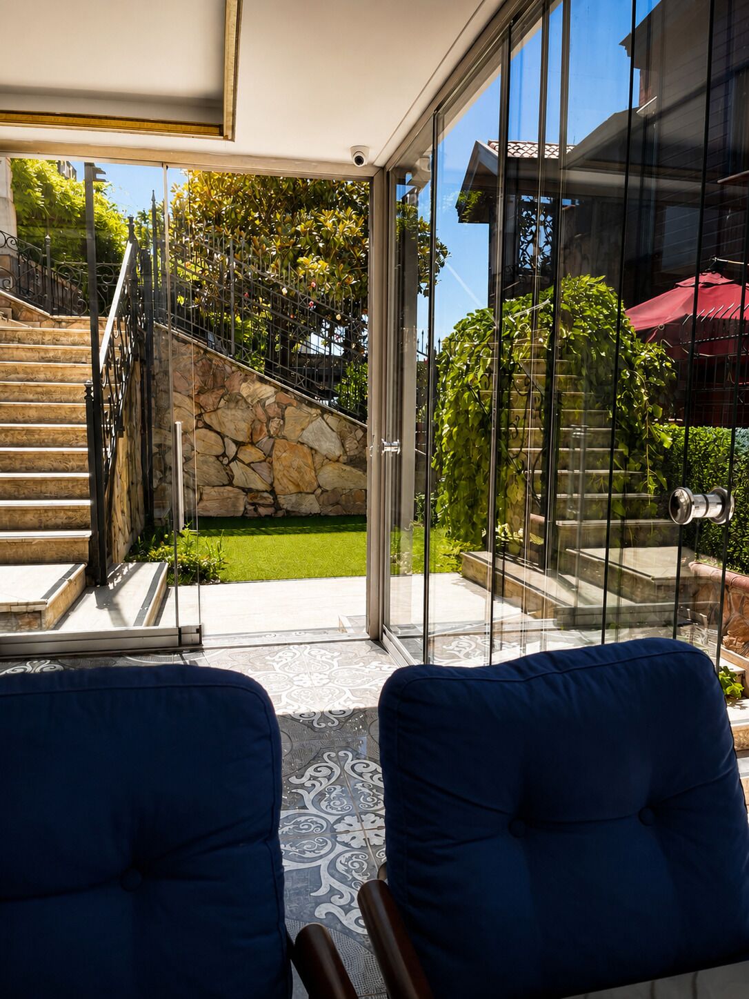 A modern interior with a glass door leading to a stone staircase and a garden.