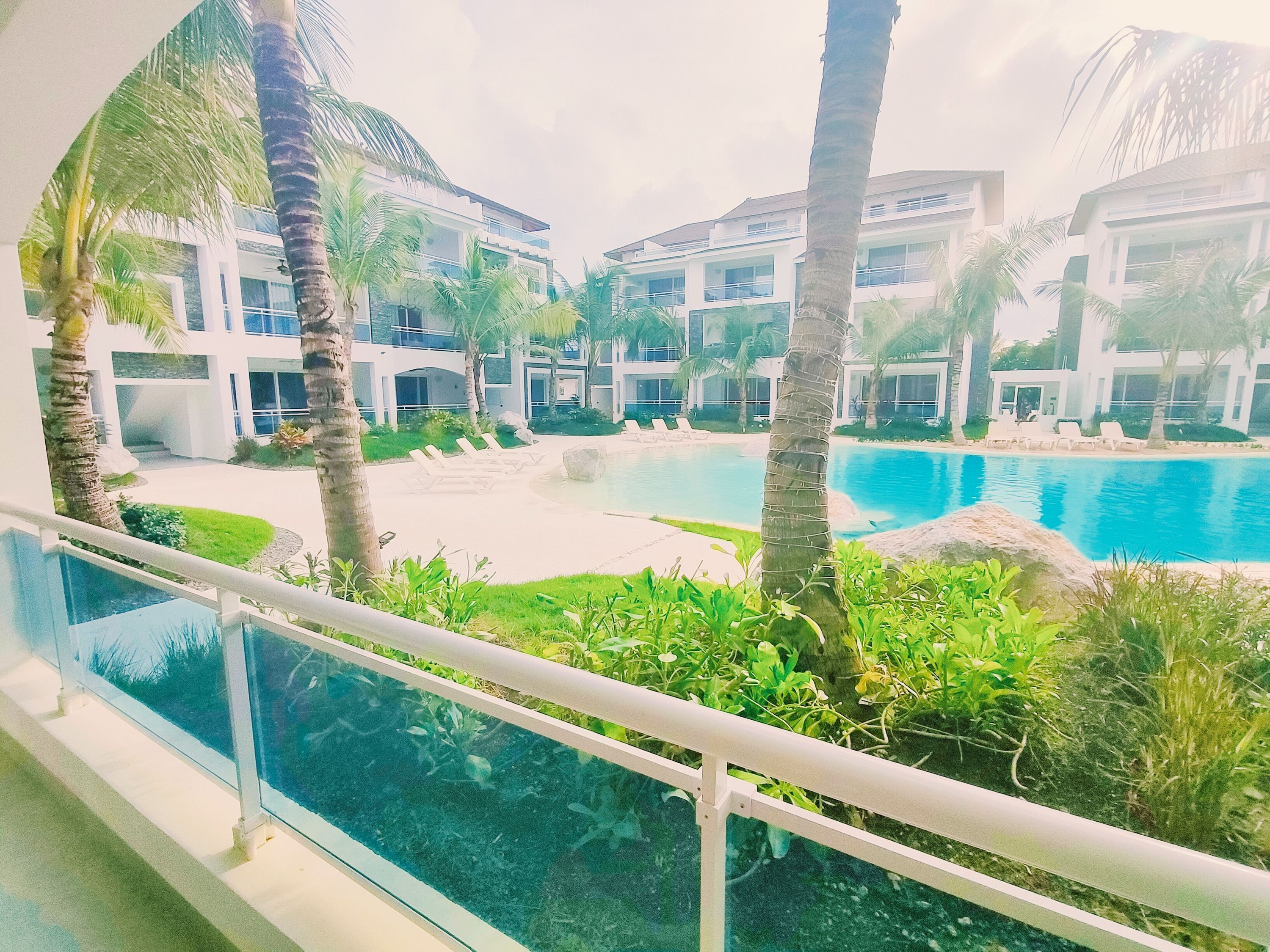 A modern resort with a pool, palm trees, and a view of the buildings.
