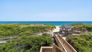 A wooden boardwalk leading to a beach with a gazebo.