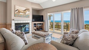A living room with a fireplace, a flat-screen TV, and a sofa with patterned cushions.