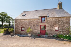 A stone house with a red door, two windows, and a chimney. - Farmhouse Holiday Home (Questembert)