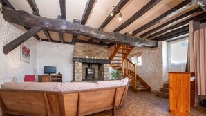 A rustic room with exposed wooden beams, a stone fireplace, a wooden bench, and a staircase. - Non-air-conditioned country cottage near a farm (Questembert)