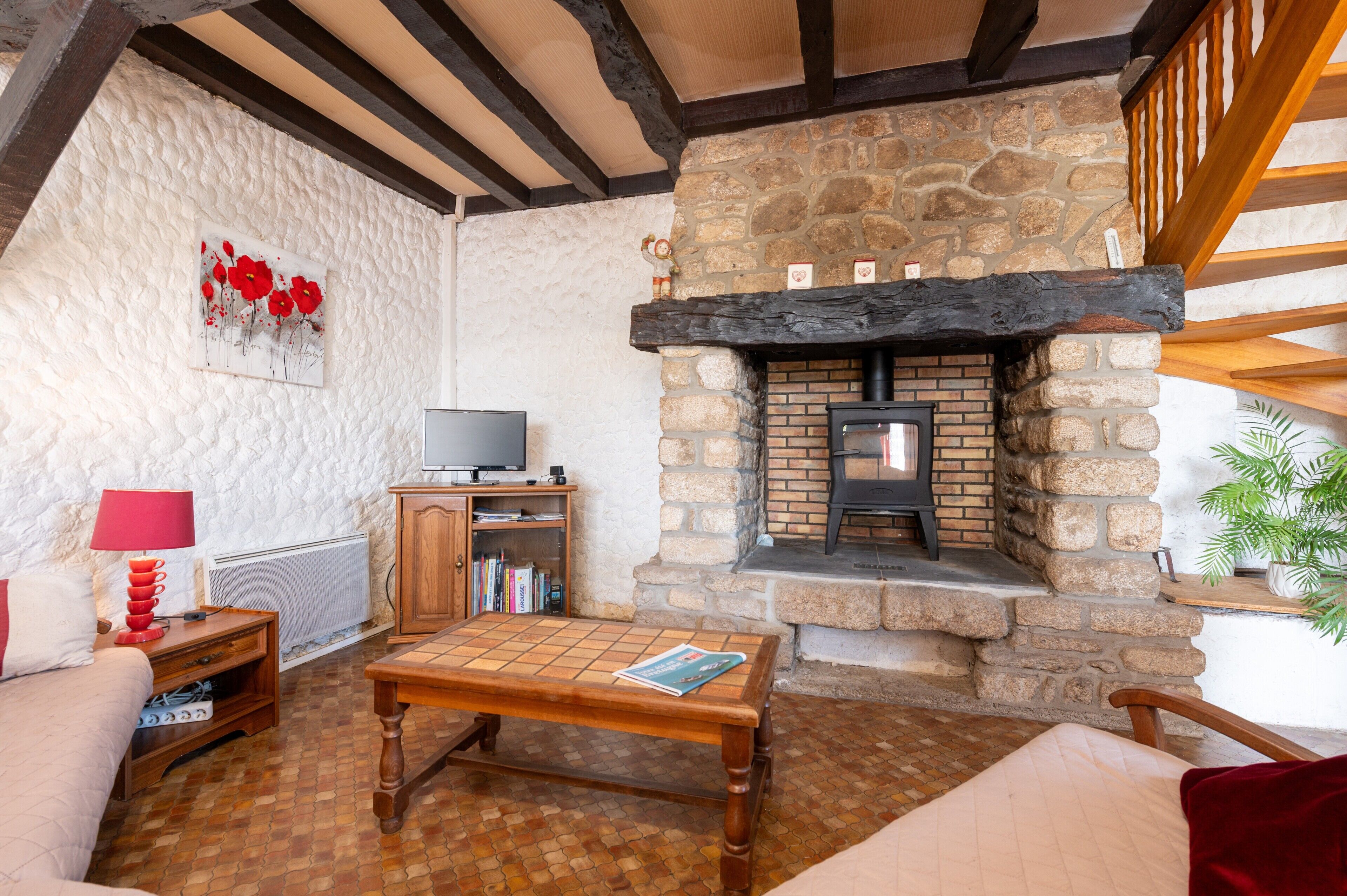 A cozy living room with a stone fireplace, a television, and a bookshelf.