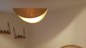 A neatly made bed with two rolled towels, a wicker headboard, a teal armchair, and a hanging light fixture. - Apartment 2/3 persons Laruns town center (Laruns)