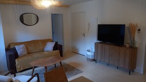 A living room with a sofa, TV, wooden cabinet, and a ceiling fan. - Apartment 2/3 persons Laruns town center (Laruns)