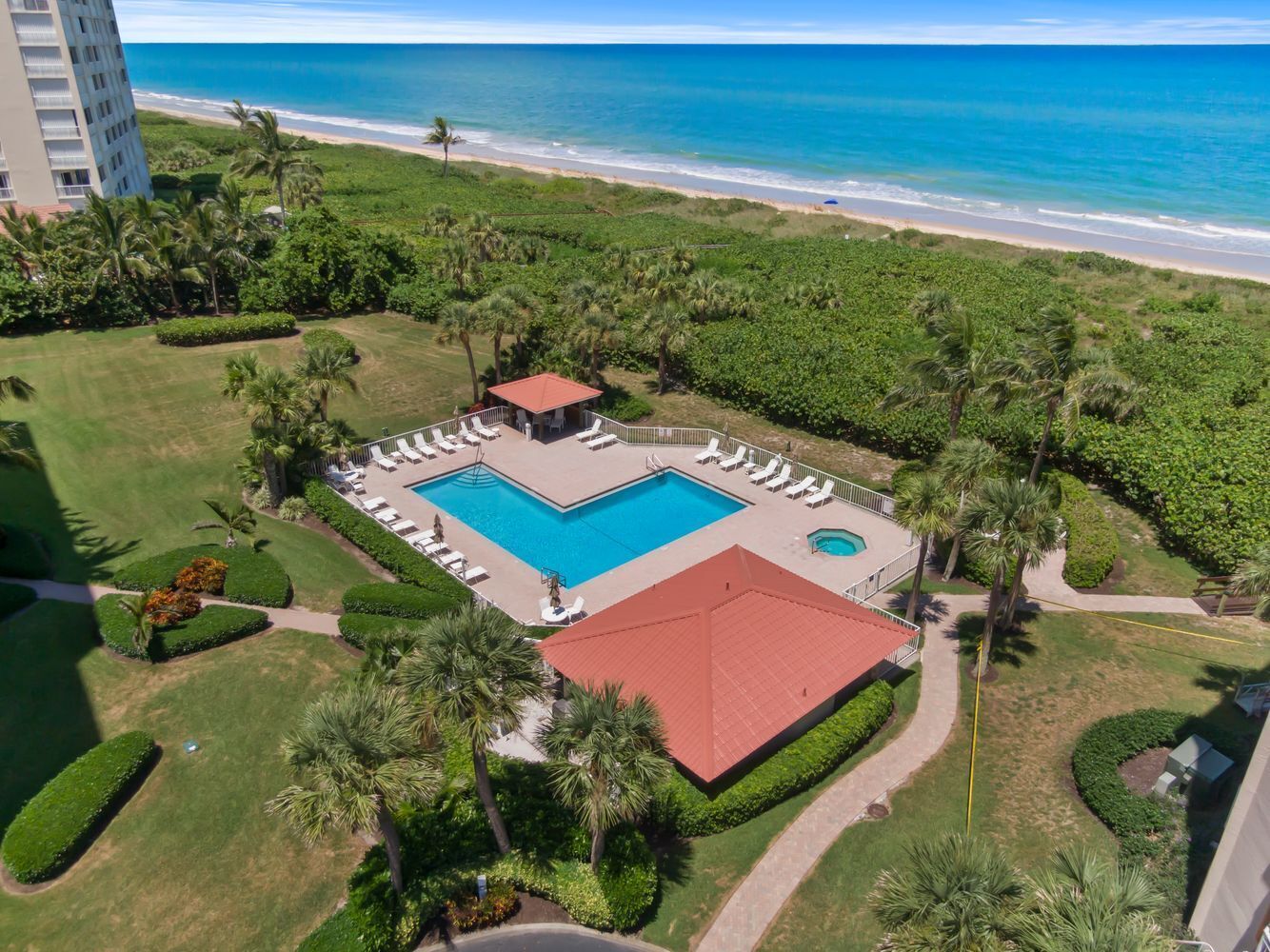 A resort with a swimming pool, lounge chairs, and a view of the ocean.