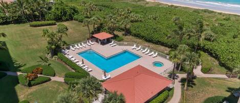 A resort with a swimming pool, lounge chairs, and a view of the ocean.