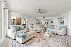 A spacious living room with a large sectional sofa, a coffee table, and a ceiling fan.