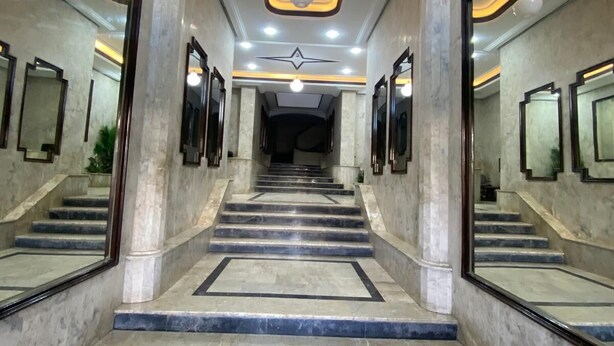 A marble staircase with a star-shaped light fixture at the top, leading to a mirrored wall.