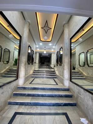 Un escalier en marbre, surmonté d’un luminaire en forme d’étoile, mène à un mur entièrement recouvert de miroirs.
