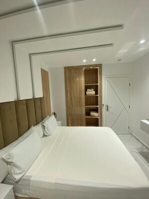 Een moderne slaapkamer met een groot bed, een houten garderobe en een spiegelwand.