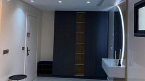 A modern hallway with a white door, a dark blue wardrobe, a white sink, and a gold floor lamp.