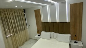 A modern bedroom with a large bed, two bedside tables, and a headboard with built-in lighting.