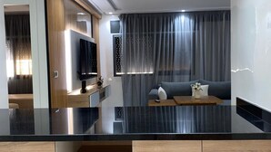 A modern kitchen with a black countertop, wooden cabinets, and a built-in TV.