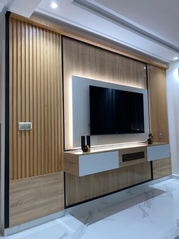 Een moderne entertainmentkast met een flatscreen televisie, houten lambrisering en geïntegreerde opbergladen.