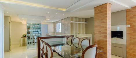 A modern kitchen with a glass dining table, wooden chairs, and a brick accent wall.