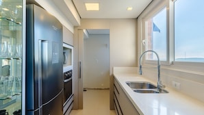 A modern kitchen with a stainless steel refrigerator, oven, and a double sink with a window above.