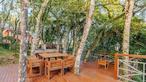An outdoor wooden deck with a table and benches, surrounded by trees.