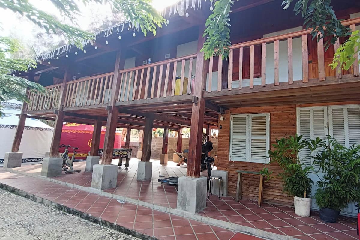 A wooden building with a balcony, tiled flooring, and potted plants.
