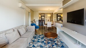 Una sala de estar moderna con un sofá, una zona de comedor y una cocina al fondo.